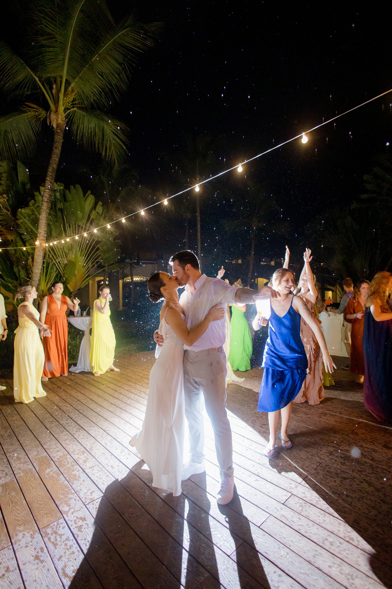 Noivos dançam com os convidados em uma festa de casamento à noite