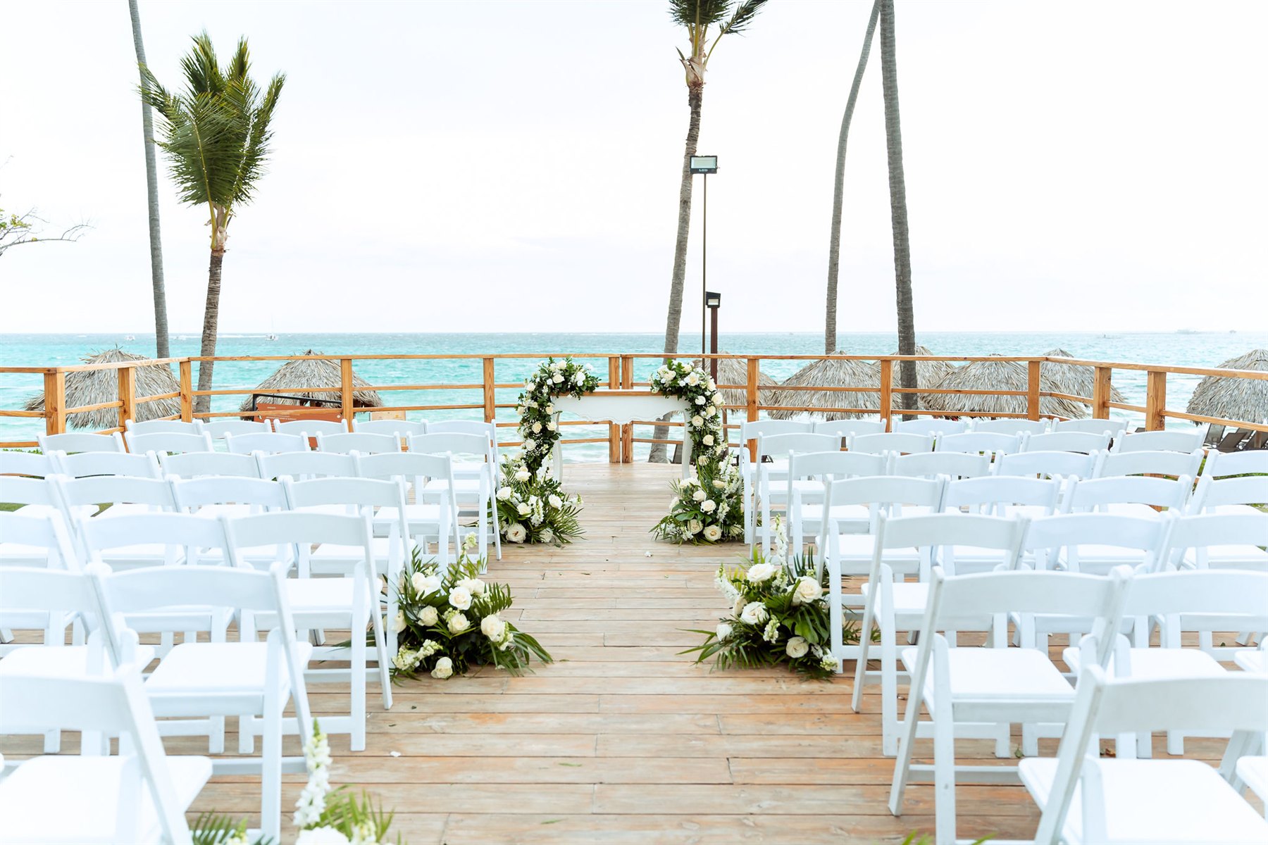 Altar de casamento e cadeiras brancas organizadas diante do mar