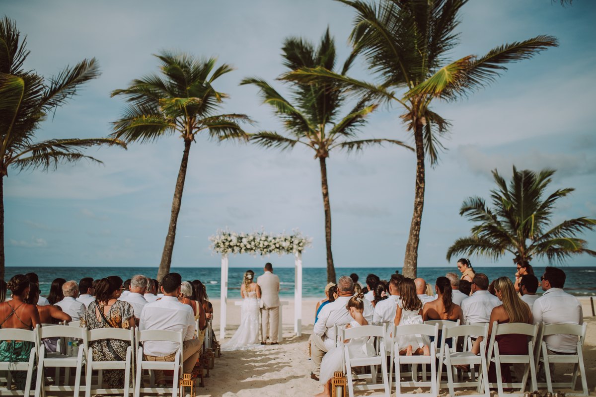 Recepção de casamento ao ar livre com mesas voltadas para o mar e coqueiros